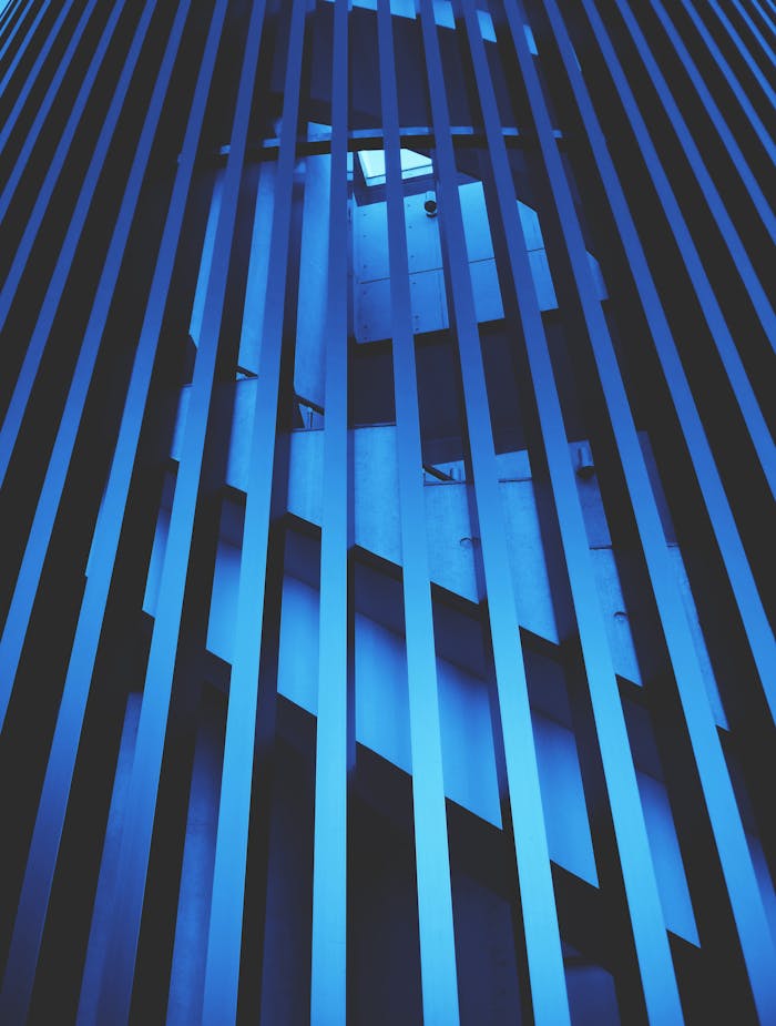 Blue-toned vertical view of modern architectural elements with lines and shadows.